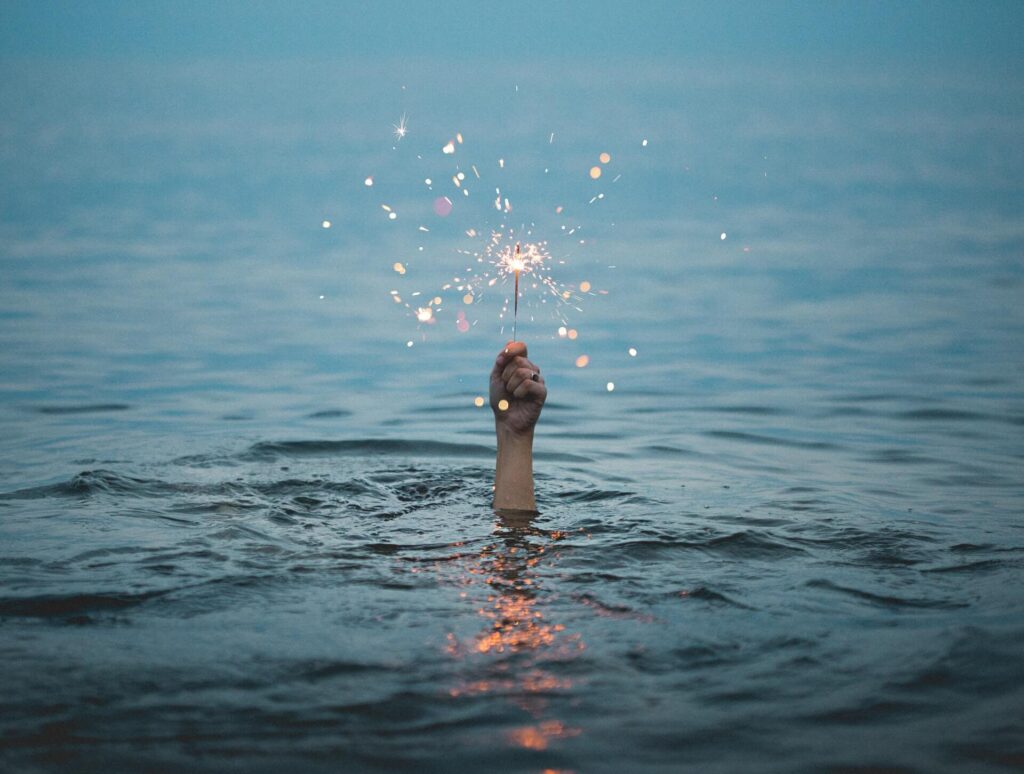 Hand raised from water holding sparkler