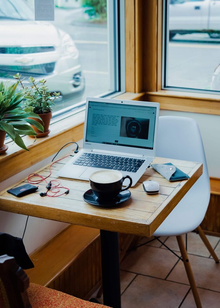 Laptop coffee and headphones at small corner table