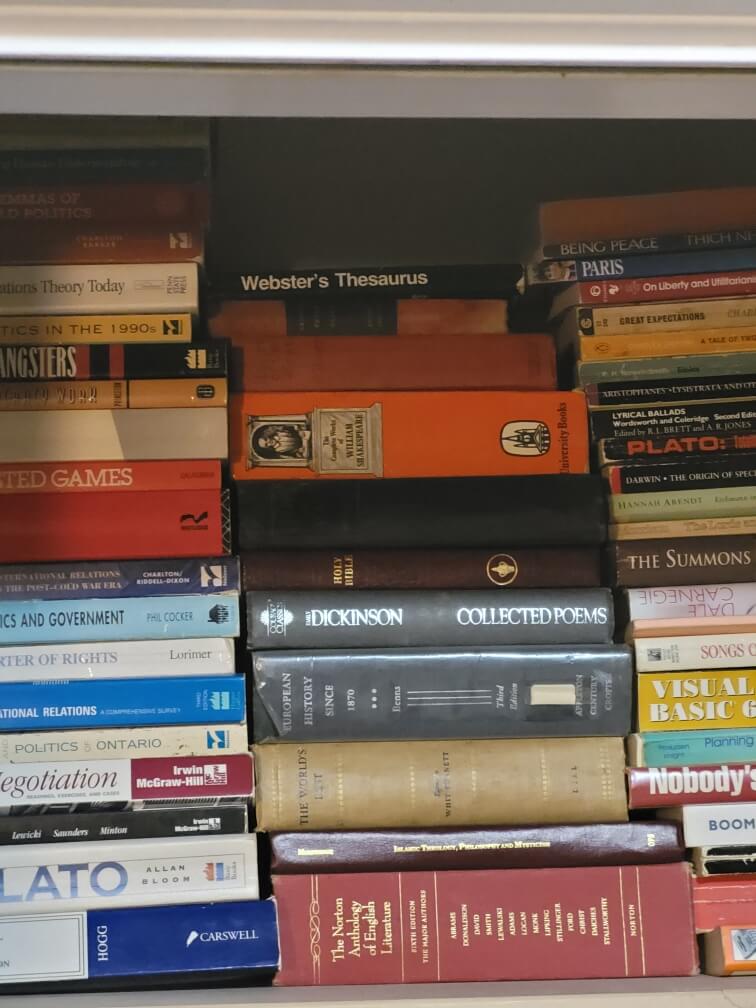 Stack of classic boos such as Plato and Dickinson on small bookcase