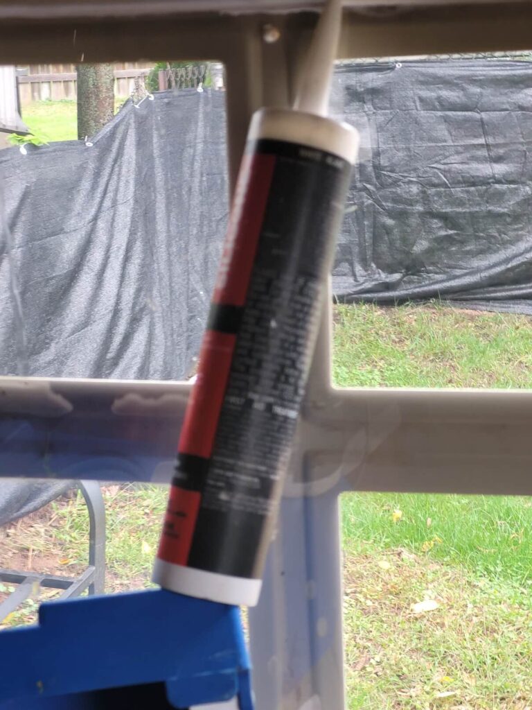 Tube of window sealant leaning against window sitting on a ladder