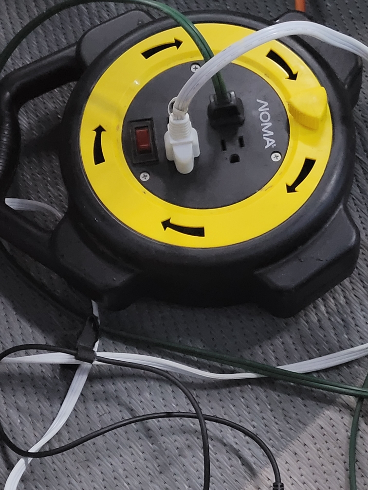 An extension cord reel with 4 outlets and 2 cords plugged into it.