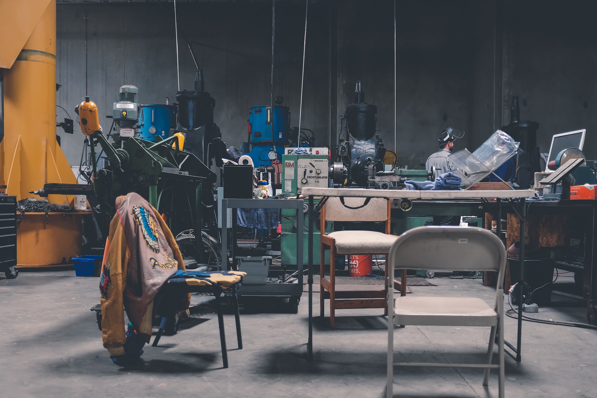 A temporary garage office with folding table and chairs as well as tools in the backgrond