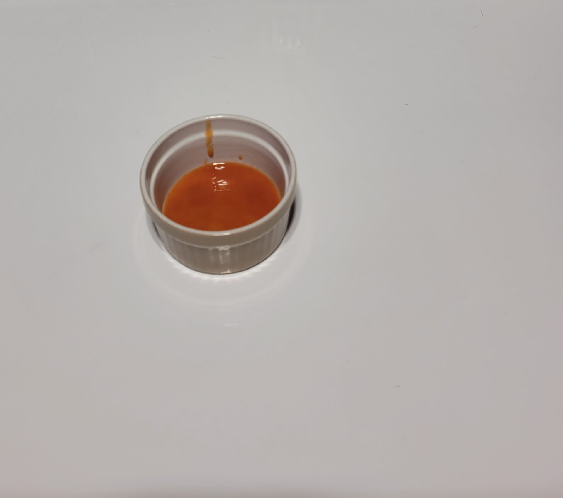 A small container of hot sauce on a white backdrop as an example of homemade hot sauce production number 85 on our list of backyard business ideas